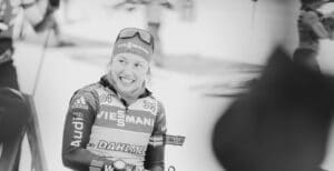 Laura Dahlmeier im Rennanzug lächelt nach dem Wettkampf, Schwarz-Weiß-Aufnahme mit ruhigem Ausdruck.