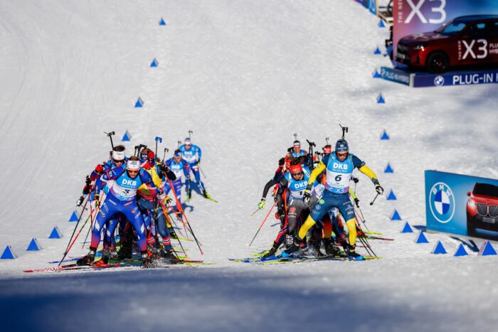 Neue-Startzeiten-fuer-den-BMW-IBU-Weltcup-Biathlon-2026_gt2a0222_0 Enges Starterfeld der Herrenstaffel läuft im Pulk eine Schneepassage hinauf.