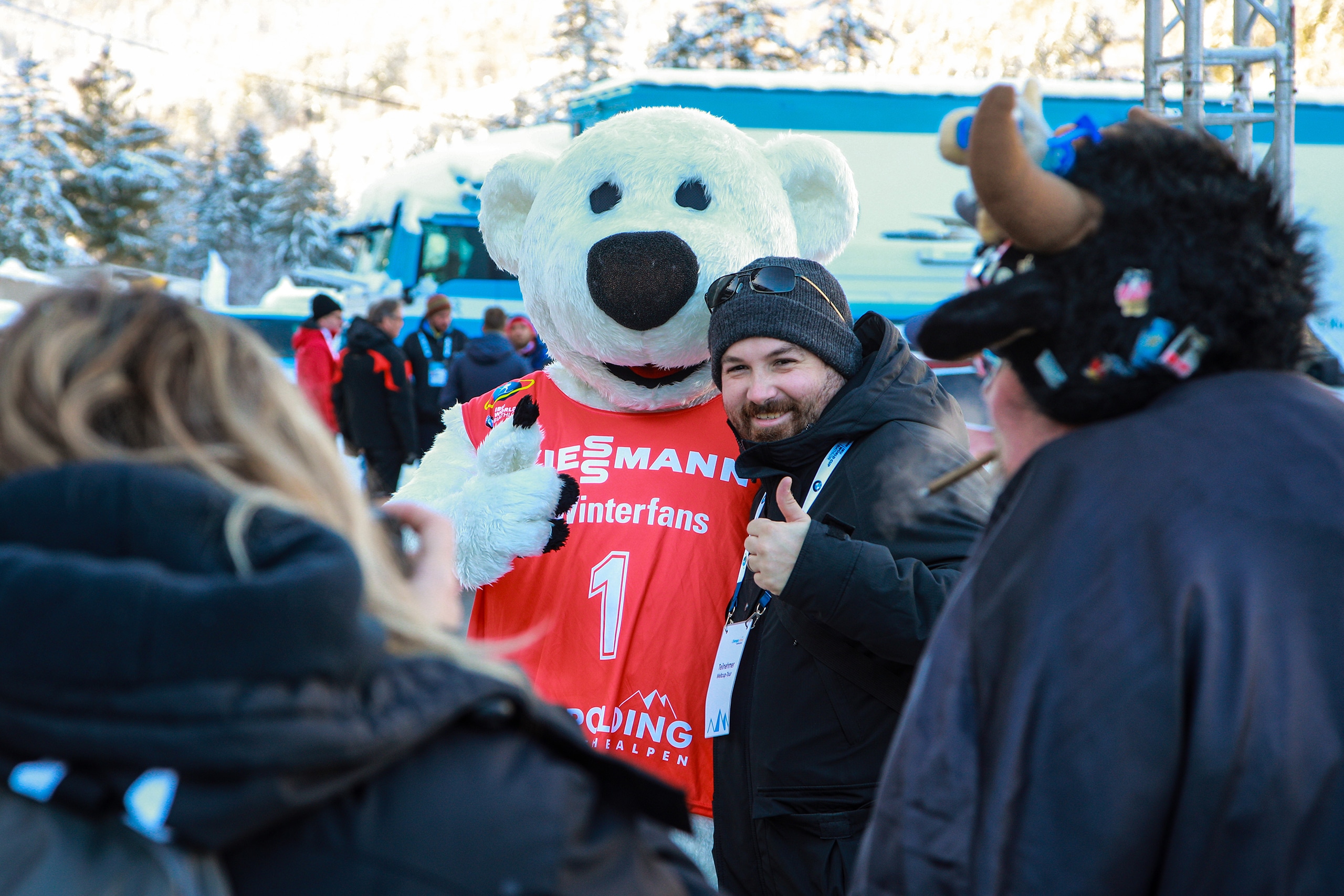 Besucher posiert lächelnd mit einem Eisbärenmaskottchen im Fanbereich der Chiemgau Arena.