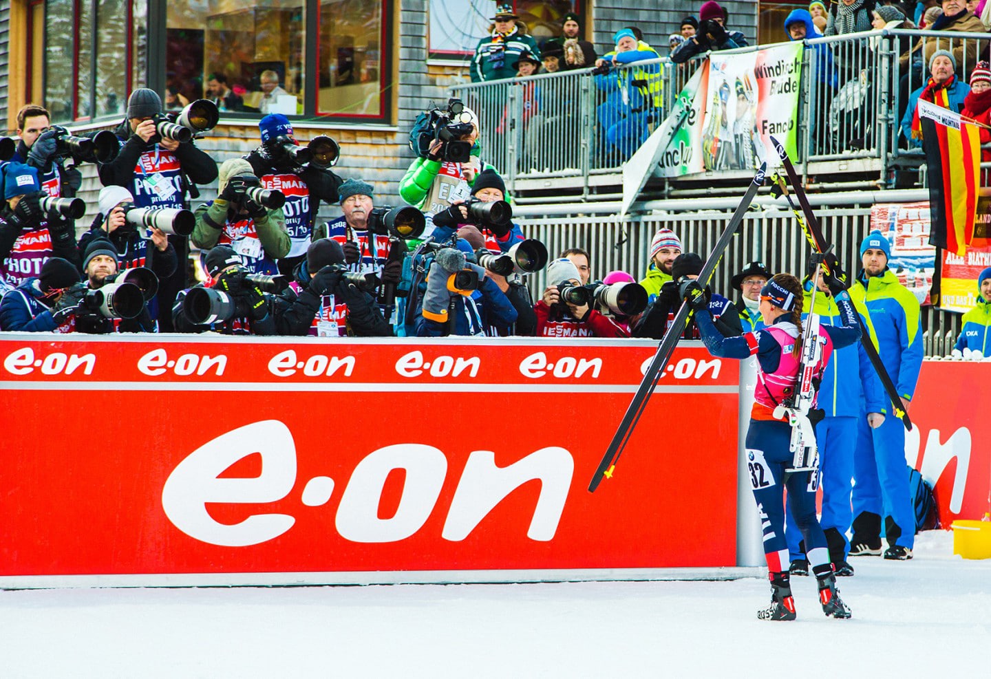 Fotografenreihe mit großen Teleobjektiven begleitet eine Biathletin im Zielbereich.