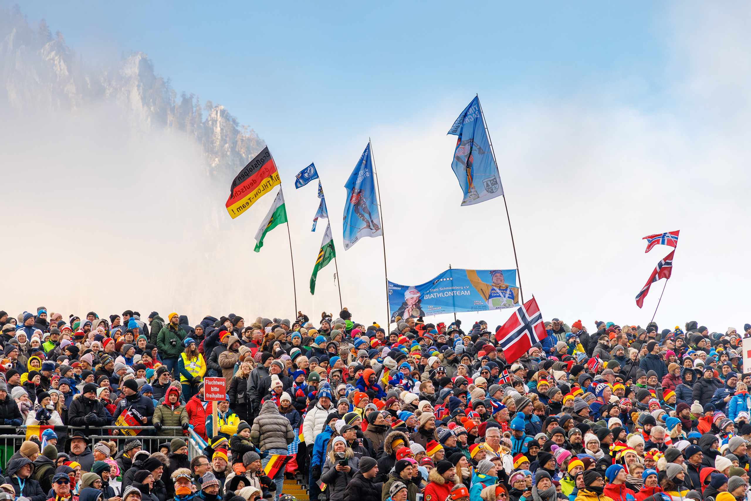 Große jubelnde Zuschauermenge mit Fahnen verschiedener Nationen beim Biathlon in Ruhpolding.