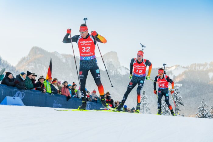 Sprint_Maenner_GT2A3453 Drei deutsche Biathleten im Sprint laufen dicht hintereinander vor jubelnden Zuschauern.