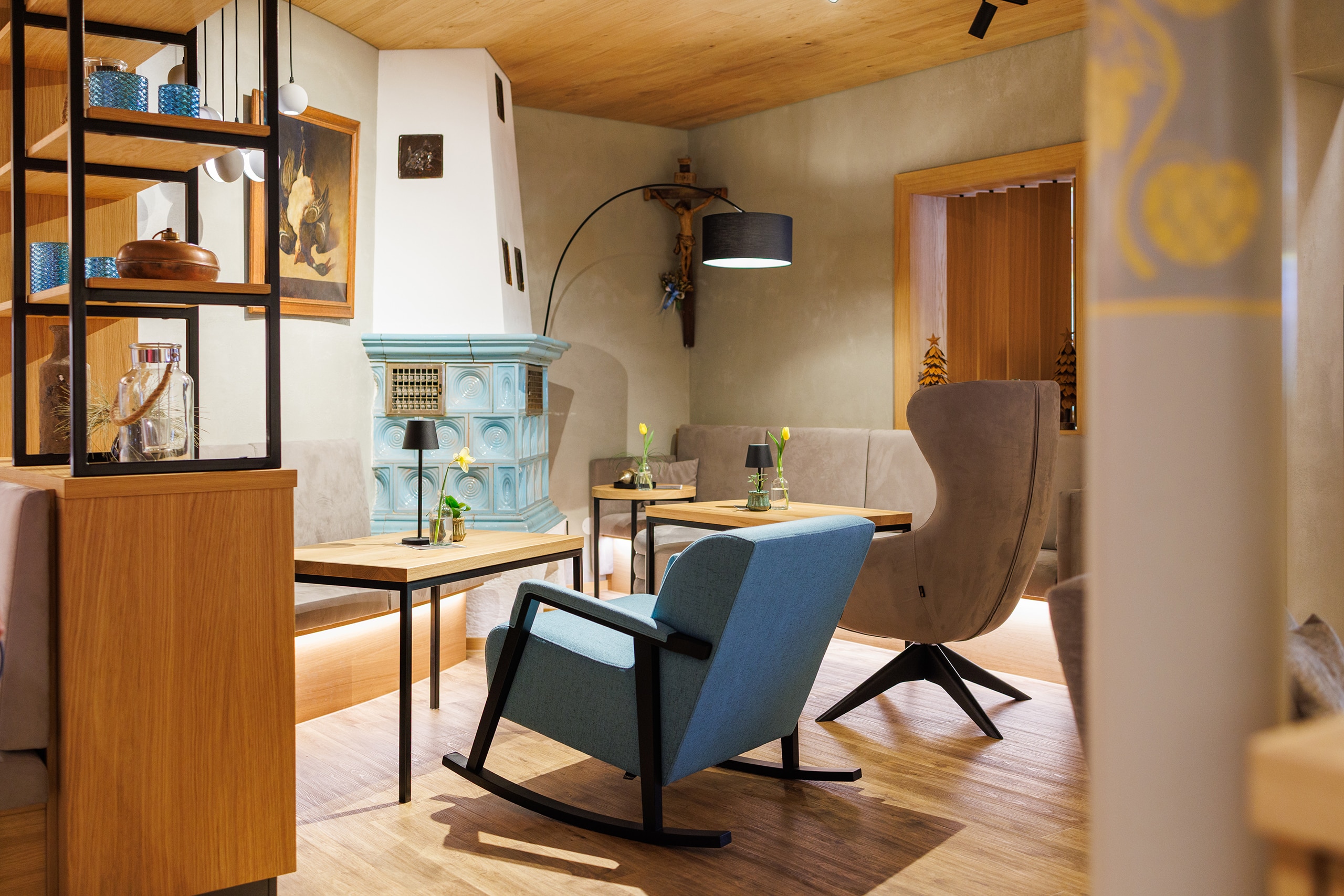 Gemütlicher Loungebereich mit blauem Kachelofen, Sesseln und Holzelementen in einer Unterkunft in Ruhpolding.